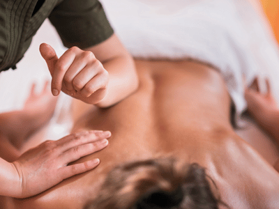 Sports massage at Everest Therapeutics in Vancouver, massage therapist pressing an elbow into a client's low back.